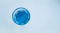 Blue glass with fresh purified drinking water on a light background.