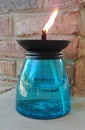 Blue glass lantern with flame in front of brick wall