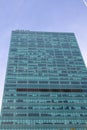 blue glass office tower with some white clouds in the sky