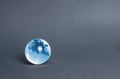 Blue glass planet globe on a gray background. Globalization and markets. Preservation of the environment and reduction of harmful