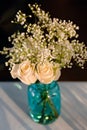 Blue Glass Vase Filled With White Roses and Babies Breath Bouquet on a White Tablecloth Royalty Free Stock Photo