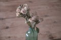 Blue glass vase with small bouquet of dried roses on wooden table Royalty Free Stock Photo
