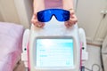 Blue glasses to protect your eyes from laser radiation. hands on top of the laser hair removal machine