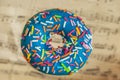 Blue glaze donut with colorful sprinkles on abstract vintage music background. Sweet food, romantic mood concept Royalty Free Stock Photo