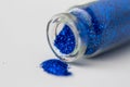 Blue glitters poured from small glass bottle