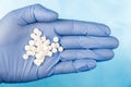 Blue-gloved hand pulls a handful of white pills Royalty Free Stock Photo