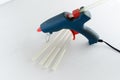 Blue glue gun and hot melt rods on white background Royalty Free Stock Photo