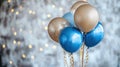 Blue and gold balloons hanging with sparkling string lights in background