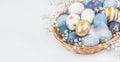 Blue and gold Easter eggs in wicker basket with copy space on white background Royalty Free Stock Photo