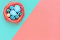 Easter eggs in nest on coral and aqua colored background. Top view, flat lay, copy space