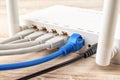 Blue and gray network cable plugs connected to the white Wi-Fi wireless router on a wooden desk. Close-up of home or office wlan Royalty Free Stock Photo