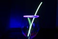 Blue and green glow stick on a wine glass and colourful light reflection with light painting aginst the dark background party