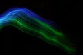 Blue-green light lines on a black background. . Color light painting.