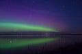 Blue green and magenta aurora borealis reflected over a lake