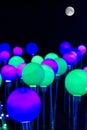 Blue, green and pink bulbs of light in the night sky under the moon - modern light show Royalty Free Stock Photo