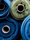 Blue and green rolls of knitted fabric. Woven factory or warehouse