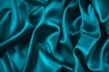 Blue green silk satin fabric. Teal color elegant background. Liquid wave or silk wavy folds. Royalty Free Stock Photo