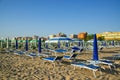 Blue and green umbrellas and chaise lounges on the beach of Rimini in Italy