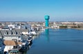 Blue green water tower by bay inlet lined with shore houses that have boat slips