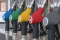 Blue, green, yellow, red and gray fuel pistols on fuel station close-up