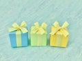 Blue, green, and yellow three square gift boxes on a blue-green-grey watercolor textured background Royalty Free Stock Photo