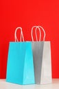 Blue and grey shopping or gift bags on wooden desk against red background