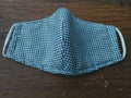 Blue grid pattern cotton fabric/cloth face protective masks on brown wooden background. It is used to protect dust, smoke, germs