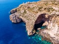 Blue Grotto in Malta. Pleasure boat with tourists runs. Natural arch window in rock. Aerial top view. Royalty Free Stock Photo