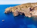 Blue Grotto in Malta. Pleasure boat with tourists runs. Natural arch window in rock. Aerial top view. Royalty Free Stock Photo