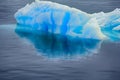 Blue growler (piece of iceberg) with reflection in calm water Royalty Free Stock Photo