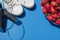 Gymnastic rug, jump rope, sports shoes, plate with strawberries on it. Diet and exercise. Top view. Copy space Royalty Free Stock Photo