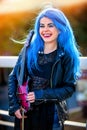 Blue hair woman buskers with violin outdoor in in sun shine.