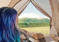 Blue hair woman resting in a tent and looking at mountain. Royalty Free Stock Photo