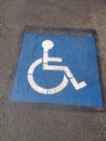 Blue handicap parking sign in the middle of a black tarmac