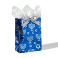 A blue Hanukkah gift bag with menorah and Star of David patterns, filled with white tissue paper and a silver bow Royalty Free Stock Photo