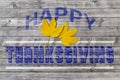 Blue Happy Thanksgiving on wooden background with two yellow leaves Royalty Free Stock Photo