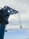 Blue harbor crane with suspended hook and white cloudy sky. Heavy load dockside cranes in port, cargo container yard. Industrial Royalty Free Stock Photo