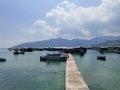 The blue harbour with the moored yachts, fishing boats and a long narrow wooden pier