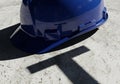Blue hard hat casting a shadow on architectural plans for construction and safety projects Royalty Free Stock Photo