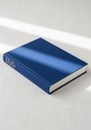Blue hardcover book with no visible title, lying on a light-colored surface. Sunlight Royalty Free Stock Photo