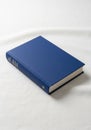 Blue hardcover book on a white fabric surface. The book has a smooth cover and an Royalty Free Stock Photo
