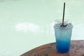 Blue Hawaii Italian soda and tubes in plastic glass on wooden table. Royalty Free Stock Photo