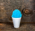 Blue Hawaiian Shave ice, Shaved ice or snow cone dessert in a plain white cup on a rustic wood background.