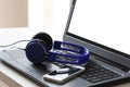 Blue headphones and a smart phone rest on a laptop computer with clipping path on the pc screen and copy space for your text