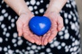 Blue heart in the hands of a woman in a polka dot dress