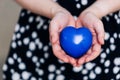 Blue heart in the hands of a woman in a polka dot dress