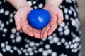 Blue heart in the hands of a woman in a polka dot dress