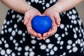 Blue heart in the hands of a woman in a polka dot dress