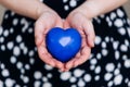 Blue heart in the hands of a woman in a polka dot dress