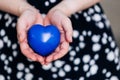 Blue heart in the hands of a woman in a polka dot dress